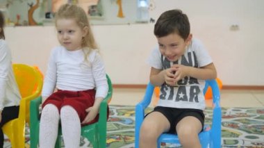 Çocuk Oyun Odası geliştirmek. Sınıflar eğlenceli sırasında duygular genç çocuk. Çocuk üst üste sandalyelere oturmak. Çocuk bir neşeli ifade inşa ediyor. antics