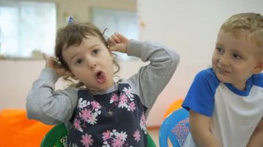 Çocuk Oyun Odası geliştirmek. Sınıflar eğlenceli sırasında duygular genç çocuk. Çocuk üst üste sandalyelere oturmak. Çocuk bir neşeli ifade inşa ediyor. antics