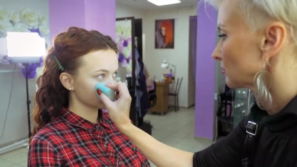 Gezicht make-up. Afstemming van de huidtextuur met een spons en poeder. — Stockvideo