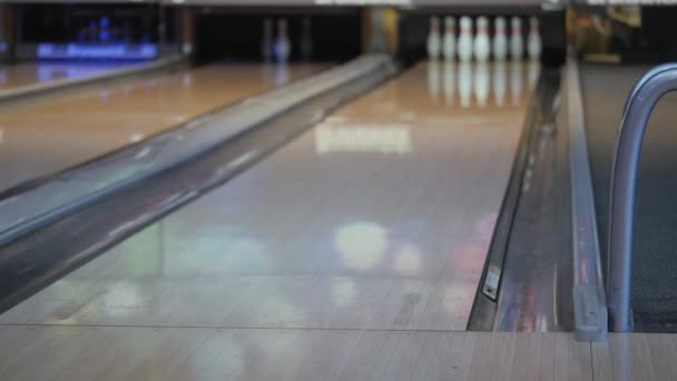 Szórakozás bowlingozni. Korcsolyagolyók a pályán azzal a céllal, hogy leüt csapok. — Stock videók