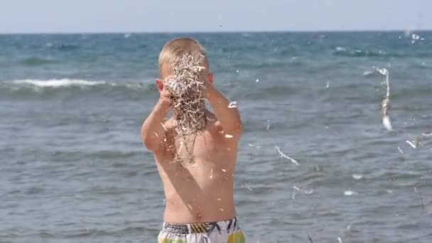 Vacaciones de verano en playa. Emociones de los niños. El niño desarrolla oropel en el viento . — Vídeo de stock