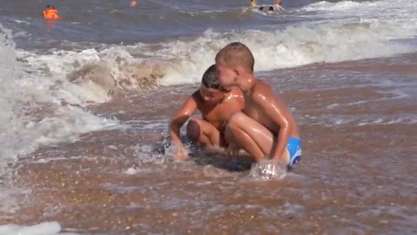 Wakacje na plaży. Dzieci w szalejących falach. — Wideo stockowe