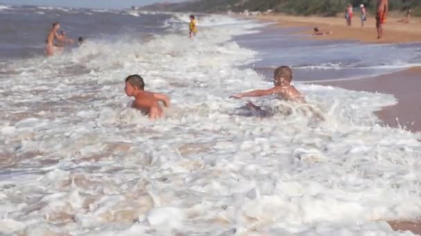 Sommerurlaub am Strand. Kinder in den wütenden Wellen. — Stockvideo