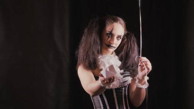 Kolay Cadılar Bayramı makyajı. Yüzünde resim olan kız. Kız beyaz kağıt bir tekneyle elini uzatıyor..