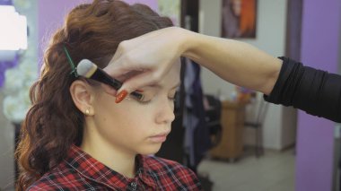 Kolay Cadılar Bayramı makyajı. Güzellik salonundaki kız. Modelin yüzüne stilistik bir model uyguluyorum. Usta bir stilistin işi..