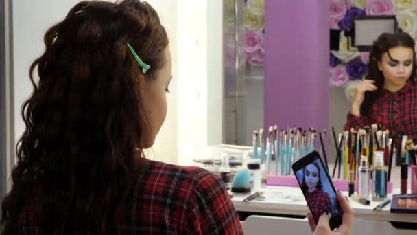 简单的万圣节化妆。 在美容院里的女孩用智能手机给自己拍照. — 图库视频影像