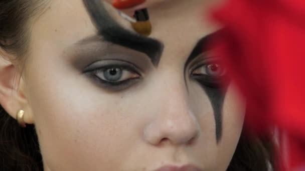 Gemakkelijke Halloween make-up. Meisje in een schoonheidssalon. Het aanbrengen van een stilistisch patroon op de voorkant van het model. Het werk van een meester stylist. — Stockvideo