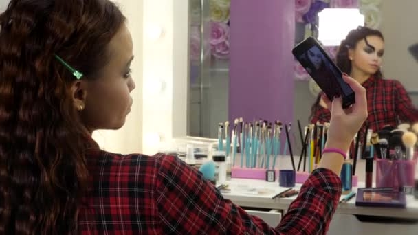 Lätt Halloween makeup. Flicka i skönhetssalong tar bilder på sig själv på en smartphone. — Stockvideo