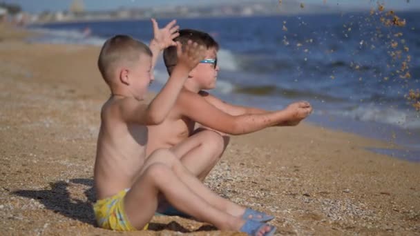 Descanse en el mar con niños. Los chicos vomitan una concha con arena. Emociones de los niños. Los chicos tiran arena . — Vídeos de Stock