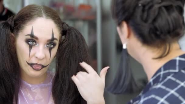 Maquillaje fácil de Halloween. Las emociones del cliente y el amo. La chica se ríe y se cubre los labios con la mano . — Vídeos de Stock