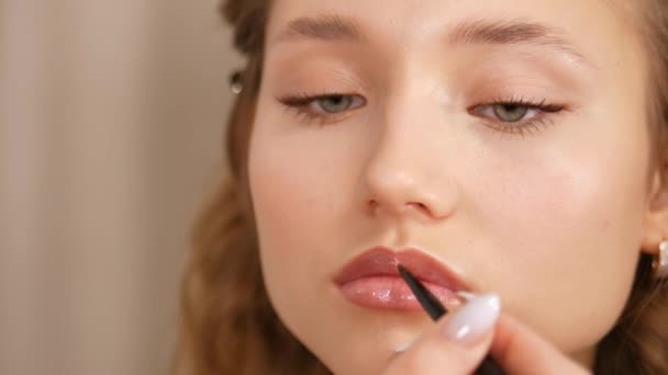 Make-up eines jungen Mädchengesichts. Farbe auf die Lippen des Mädchens auftragen. — Stockvideo