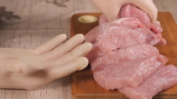 Pork is on the Board. Sliced pork meat. Take a piece of meat in your hand and throw it down. Cooks hands were clad in latex gloves. — Stock Video