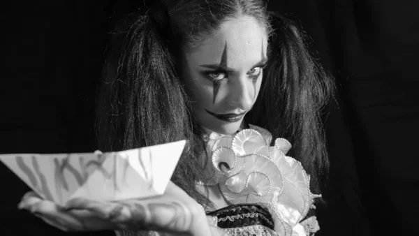 Retrato de uma mulher. A menina segura um barco branco em sua palma aberta. Um palhaço com um sorriso num espartilho. Modelo com maquiagem para o Halloween . — Fotografia de Stock