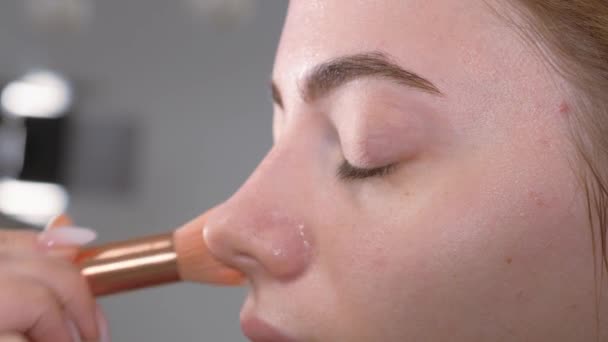 Het voorbereiden van de modellen huid voor het aanbrengen van make-up. Verwerken van het gezicht met een borstel met een poeder Foundation aangebracht. — Stockvideo