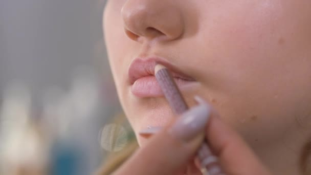 Obra de un maquillador. Acaricia el contorno de los labios con un lápiz corrector marrón . — Vídeos de Stock
