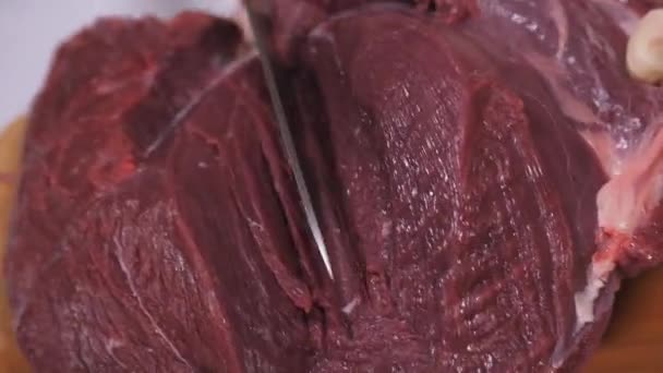 Обрезание мяса дикого лося. Тёмное сырое мясо. Резка на деревянной доске . — стоковое видео