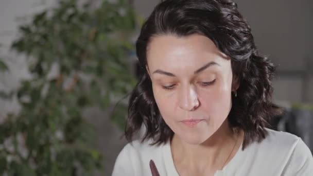 De ochtend make-up aanbrengen. De brunette creëert een gezicht tekening voor zichzelf voor vertrek naar het werk. — Stockvideo