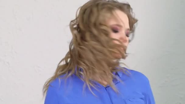 Young blonde girl turns her head. Hair is flying in different directions. The face is hidden behind curls of hair. — Stockvideo