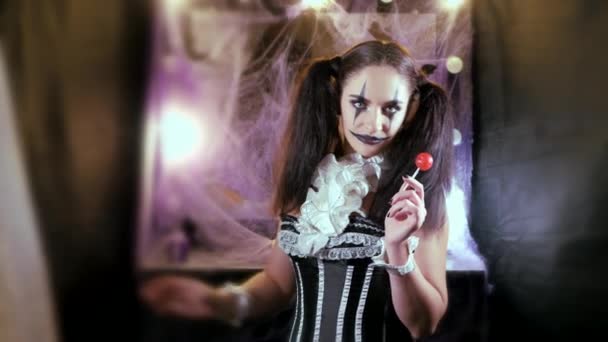 Portrait of a woman. A clown with a smile in corset with a white collar on the neck. Model with makeup for Halloween. Woman flirting. The girl with the red Lollipop. — Stock Video