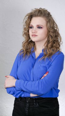 Sarışın, kıvırcık saçlı, açık mavi gömlekli bir kız..