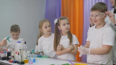 Chemical experiments for children. Fun experiments for children. A woman conducts cognitive science lessons. Boy wears safety glasses and wears transparent gloves.