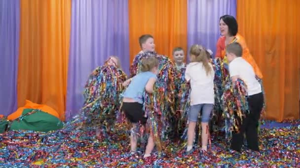 Las cintas de colores vuelan en diferentes direcciones. Los niños se divierten. Niños brillantes emociones . — Vídeos de Stock