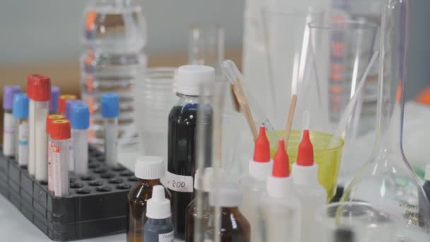 Pratos químicos e acessórios são colocados na mesa. Tubos de ensaio com reagentes . — Vídeo de Stock