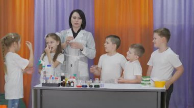 Chemical experiments for children. boy pours reagents from a test tube into a plastic Cup for a chemical experiment. Fun experiments for children. A woman conducts cognitive science lessons.