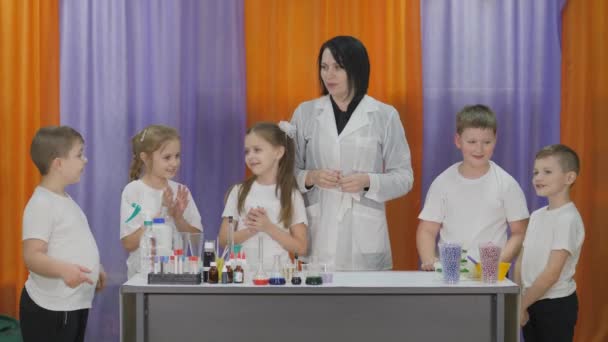 Experimentos químicos para niños. Divertidos experimentos para niños. Una mujer imparte clases de ciencias cognitivas. Los niños aplauden con aprobación mientras esperan a que comience la clase . — Vídeos de Stock