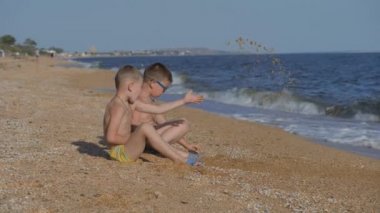 Çocuklarla birlikte denizde dinlen. Çocuklar kumla bir kabuk attılar. Çocukların duyguları işte. Çocuklar kum atıyor..