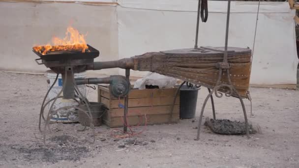 A street forge, a fire burning in the hearth, an anvil with a tool laid out. — Stock video