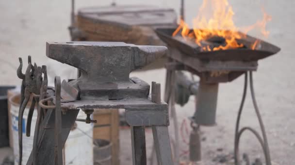 A street forge, a fire burning in the hearth, an anvil with a tool laid out. — Stockvideo