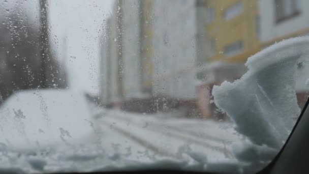 Un trozo de nieve desciende sobre el parabrisas del coche. Limpiaparabrisas de coche empezar a limpiar el vidrio . — Vídeos de Stock