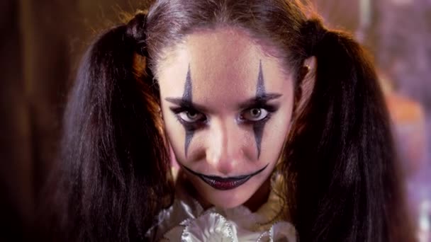 Retrato de una mujer. Un payaso con una sonrisa en corsé con un cuello blanco en el cuello. Modelo con maquillaje para Halloween. La mujer golpea sus pestañas . — Vídeos de Stock