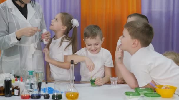 Expériences chimiques pour les enfants. Femme verse une substance verte dans une bouteille en plastique blanc. Les enfants sont surpris. La pièce est remplie de fumée artificielle . — Video