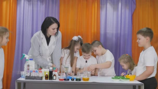 Expériences chimiques pour les enfants. Boy ajoute des gouttes vertes à un verre clair de liquide. La pièce est remplie de fumée artificielle . — Video