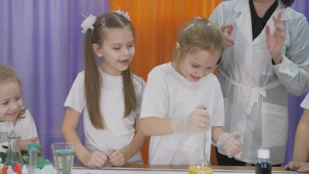 Expériences chimiques pour les enfants. Les enfants secouent une fiole, fermée avec un bouchon de liège, avec un liquide jaune. La pièce est remplie de fumée artificielle . — Video