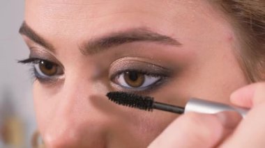 Makyaj yapıyorum. Genç kız aynaya bakar ve maskarasını sürterek gözlerinin kirpiklerine sürter..