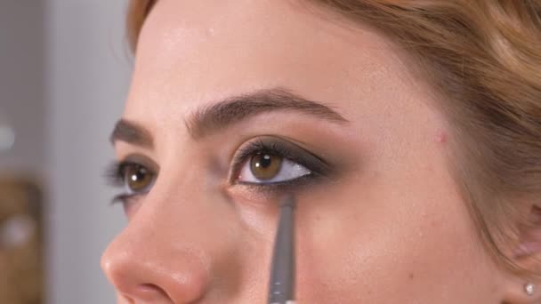 Používám make-up. Dává mladým dívkám výraz v očích. Pohladit obrys oka tužkou na make-up. — Stock video