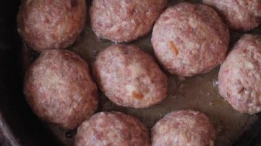 Ev yemeği. Köfteleri dökme demir tavada ayçiçeği yağında kızartıyorlar. Yağ tavada cızırdıyor. Buhar köfteden geliyor. Köfteleri tavaya çift sıra yerleştirmek.