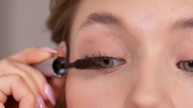 Makyaj yapıyorum. Genç kız aynaya bakar ve maskarasını sürterek gözlerinin kirpiklerine sürter..