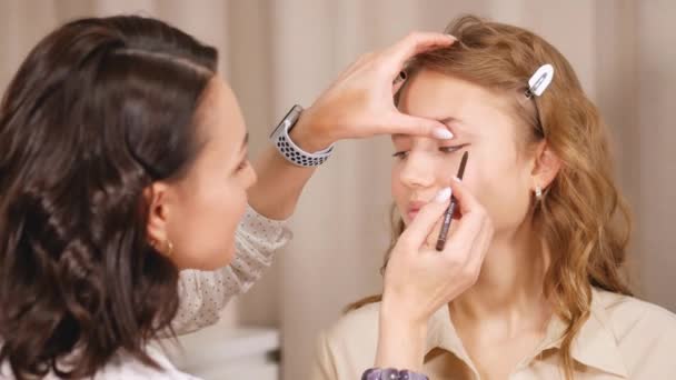 Aplicando maquillaje. Dando expresión a los ojos de las niñas. Acaricia el contorno de los ojos con un lápiz de maquillaje . — Vídeos de Stock