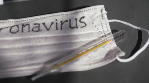 Coronavirus. Las vendas de gasa desechables médicas están sobre la mesa. Un termómetro de vidrio de mercurio descansa sobre una máscara médica protectora . — Vídeo de stock