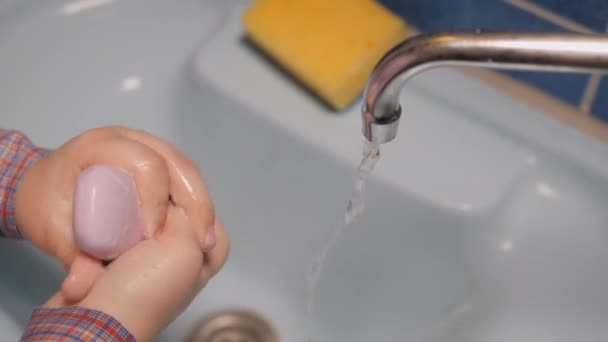 Cuidado com as mãos. Lave as mãos debaixo de água corrente. A criança lava as mãos com sabão. O rapaz lava as mãos antes de comer na casa de banho. O conceito de limpeza e higiene . — Vídeo de Stock