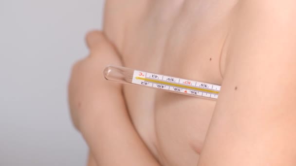 Mercury thermometer under the childs hand. Temperature measurement. Pandemic March 2020. The boy holds under his arm a means of measuring the temperature of the human body. — Stock Video