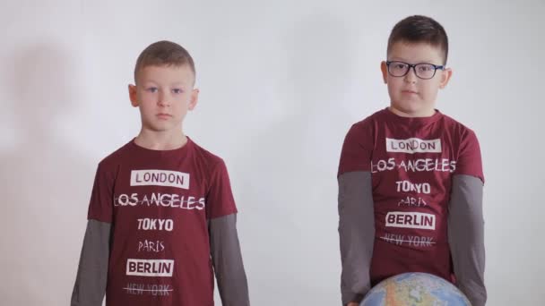 男孩拿着一个地球，一个地球的模型。小孩拿着一个标语牌，上面写着："我们都很强壮。"男孩对这种病毒很小心.大流行病2020年3月。Coronavirus. — 图库视频影像