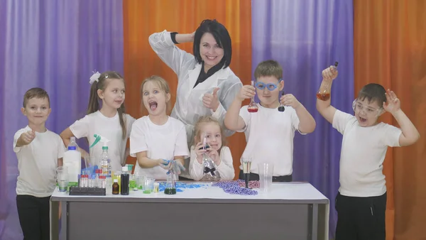 El niño sostiene frascos de líquido de color. Experimentos químicos para niños. Divertidos experimentos para niños. Los niños se divierten y aprenden. Niños brillantes emociones . —  Fotos de Stock