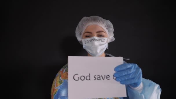 Vrouw in beschermende kleding draagt een bord dat GOD SAVE US leest. Het meisje heeft een model van de aarde, een wereldbol.. — Stockvideo