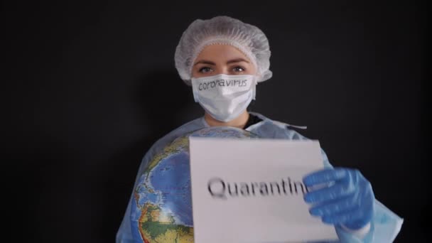 Femme en vêtements de protection tient un signe qui lit QUARANTINE. La fille tient un modèle de la terre, un globe . — Video