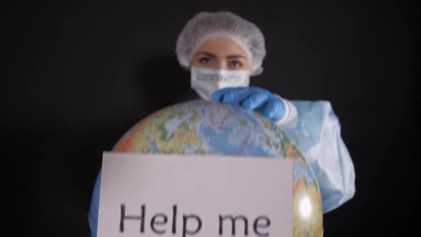 Женщина в защитной одежде держит знак, который читает ПОМОГИТЕ МНЕ. Девушка держит в руках модель Земли, глобус . — стоковое видео